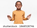Small photo of Playful dark skinned little boy having fun posing isolated with mouth full of water. Cute African boy blowing cheeks, trying hard to suppress laughter. Positive human emotions and body language