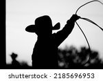 Small photo of Kid cowboy with lasso for roping in silhouette black and white closeup.