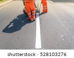 Thermoplastic spray marking machine during road construction.
Worker painting white line on the street surface (Road worker painting)

