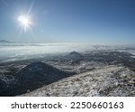 Winter snowy panorama of neighboring mountains and hills from Mount Beshtau with snow-covered and icy grass, sunny winter day
