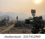 Small photo of 26 March 2023 , Kanchanaburi THailand :: Cinematography filming a documentary film at the beautiful mountain view,Film crew outdoors,Movie production at Landscape location,Red Gemini Camera