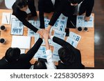 Small photo of Top view cohesive group of business people join hands together, form circle over table filled with financial report paper. Colleagues working to promote harmony and team building concept in workplace.