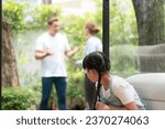 Small photo of Stressed and unhappy young girl huddle in corner crying and sad while her parent arguing in background. Domestic violence at home and traumatic childhood develop to depression. Synchronos