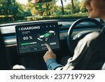 Small photo of Electric car driver checks battery charging status, range and charging limit on app screen in the car. Smart technology device show EV car recharging data of electric storage in car battery innards.