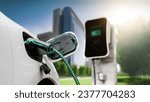 Small photo of Electric car plug in with charging station to recharge battery with electricity by EV charger cable in eco green city park. Future innovative EV car using alternative clean energy reducing CO2. Peruse