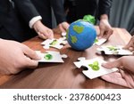 Small photo of Cohesive group of business people holding eco icon jigsaw puzzle pieces around globe Earth as eco corporate responsibility for community and sustainable solution for greener Earth. Quaint