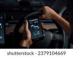 Small photo of Electric car driver checks battery charging status, range and charging limit on app screen in the car. Smart technology device show EV car recharging data of electric storage in car battery innards.