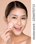 Small photo of Closeup ardent woman applying her cheek with dry powder and looking at camera. Portrait of younger with perfect makeup and healthy skin concept.