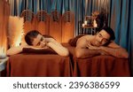 Small photo of Caucasian couple customer enjoying relaxing anti-stress spa massage and pampering with beauty skin recreation leisure in warm candle lighting ambient salon spa at luxury resort or hotel. Quiescent