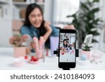 Small photo of Selective focus phone with young beautiful Asian showing cosmetic makeup lipstick matte pastel color testing bestseller collection on arm test promotion on social media online recording. Stratagem.