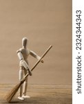 Small photo of Mini figure of storm troopers cleaning the floor using a mop on a wooden background. Miniature robot on a wooden background. Mini troopers helping in household activities.