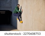 Young adult man in sportswear jumping on concrete wall during sunny afternoon in the city enjoying parkour workout