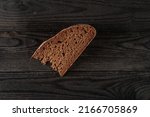 Small photo of Brown small piece of bread on black wooden table. Dark HDR photo. Simple food, meager food, poverty and malnutrition