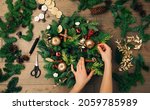 Small photo of Woman's hands decorating a Christmas wreath. New Year holiday decoration, Christmas tree wreath decoration with female's hands DIY.