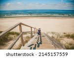 Small photo of Rare view of a little girl going down the stairs to the deserted sandy beach on the Baltic sea