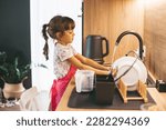 Little girl washing dishes with sponge in kitchen sink at home. Child doing chores concept.