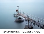 Short metal and wooden pier with steps leading into the sea.  Long exposure gives a silky smooth surface to the  water