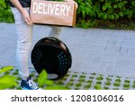 Modern future delivery. Man male guy in delivery uniform and delivery box with electric transport / eco ecology electric unicycle / self balancing wheel delivers ordered package to receiver