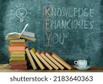 books and blackboard with drawing of a lightbulb and slogan knowledge emancipates you,learning,education,back to school concept