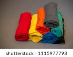Stack of colorful rolled t-shirts on gray background. The closeup photo of apparel.
