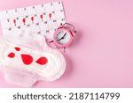 Small photo of Women's Menstrual pads (sanitary napkin) with red paper drops, a calendar of women's menstruation and an alarm clock (clock) on a pink background. The period of critical days. Space for text.