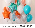 Composition of blue, silver, orange and transparent balloons with helium. Foil balloon in the shape of a star. The concept of decorating a room with helium balloons for holidays or birthdays