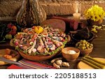 Small photo of Plate of cold cuts (fiambre) surrounded by ceremonial objects.