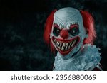 a mad evil redhead clown, wearing a white and red striped costume with a white ruff, stares at the observer with a creepy smile, in front of a dark background
