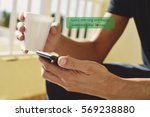 closeup of a young caucasian man with a cup of coffee in his hand sending or reading a text message with a smartphone with the text good morning and happy valentines day, I love you