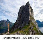 beautiful girl stands on the rocks above the precipice enjoying the view of the famous segla mountain in norway, senja island; hesten trail head, the famous norwegian fjords with mighty mountains