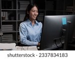 Young beautiful Asian businesswoman working overtime with her computer, working at night.
