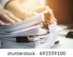 Work from Home, Businessman hands working in Stacks of paper files for searching information on work desk home office, business report papers,piles of unfinished documents achieves with clips indoor.