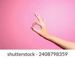 Small photo of Woman hand showing ok gesture isolated on a pink background. Ok hand sign
