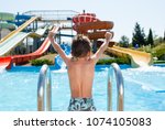 healthy happy little kid near blue swimming pool in water park with water tube slides in summer
