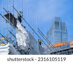 Small photo of London, UK, June 9th 2023:Scaffolders working on a tall building and removing the scaffolding poles. Concept for construction site, dangerous work, engineering, scaffold industry and copy space.