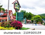 Small photo of Helen, USA - October 5, 2021: Helen, Georgia Bavarian village traditional German architecture roof and colorful house and direction sign for restaurant and park in America Oktoberfest