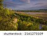 View of Missouri River bluffs and floodplain  in the evening; darkening blue sky in background; bluffs lit by setting sun