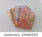 Small photo of The Indonesian currency is 100,000, 10,000 and 5,000 rupiah under folded state on white paper