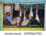 Small photo of Srinagar, India - july 02, 2015 : Raw meat hanging in a decrepit shop and meat seller waiting for customers on the street market in Srinagar, India