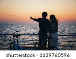 Silhouette of a couple with bikes at the beach at sunrise sky summer time, seashore summer beach at yellow blue evening horizon sea, sunset background