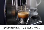 Small photo of Coffee machine filling a cup with expresso. Transparent mug in automated coffeemaker machine. Beverage drink for breakfast