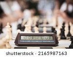 Chess digital time.Close-up and selective focus on the time clocks at the street chess tournament surrounded by chess pieces in the background. Defocused people in the background playing champion ches