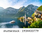 Panorama view of famous old town Hallstatt and alpine deep blue lake with tourist ship in scenic golden morning light on a beautiful sunny day at sunrise in summer, Salzkammergut, Austria
