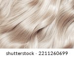 Small photo of Blond hair close-up as a background. Women's long blonde hair. Beautifully styled wavy shiny curls. Hair coloring. Hairdressing procedures, extension. White hair