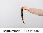 Close up photo of woman holding braided brown hair for donation