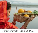 Small photo of An Indian devotee in traditional attire offers prayers to the sun during the Chhath festival , Asian woman wearing Indian jewelry . An ancient Hindu festival, dedicated to Lord Surya and Chhathi ma...