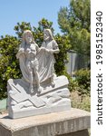 Small photo of Santa Inez, CA, USA - April 3, 2009: San Lorenzo Seminary. Station of the Cross number 10 white marble statue. Jesus stripped of garments. Green foliage in back under blue sky.