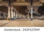 Small photo of York, UK. February 13, 2024. A railway station platform, lined by columns curves, into a main concourse. A historic 19th Century canopy is overhead and a train waits in a siding.