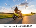 Motor biker riding on empty road with sunset light, concept of speed and touring in nature. Small motorcycle scooter