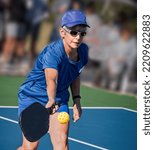 Small photo of Female pickleball player hits a volley with her right hand